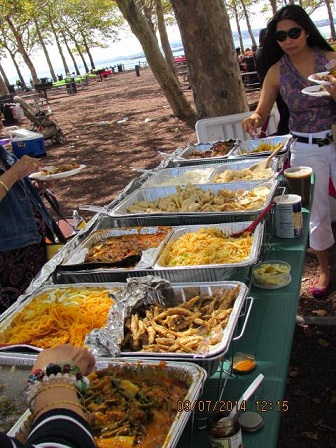 One of three picnic tables covered with trays of food