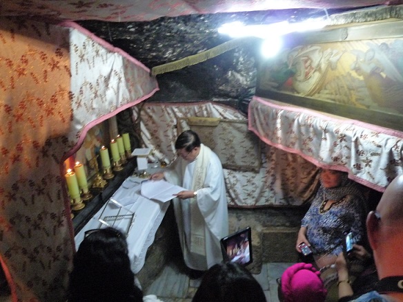 A Filipino priest leads a short Mass and candle lighting at an altar inside the Church of the Nativity in Bethlehem