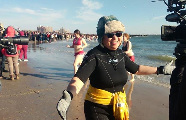 A triumphant Marilyn Abalos faces local TV cameras after braving the frigid waters. 