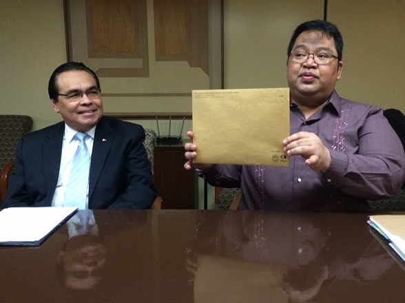 Consul Kerwin Tate holds up a brown envelope containing voting material mailed to 26K registered voters in the Northeast. Consul General Mario de Leon Jr., to his right, says voting may be done on site at the Philippine Consulate, by mail or by visiting ‘collection centers’ across the region. The FilAm Photo