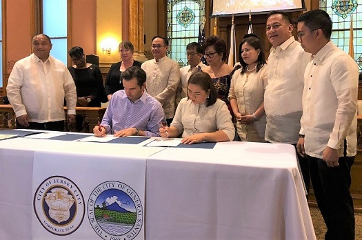 Jersey City Mayor Steven Fulop and General Santos City Vice Mayor Shirlyn Banas-Nograles sign the sister city agreement as witnessed by their respective council members. Also in photo is organizer and GenSan native Darlene Dilangalen Borromeo. The FilAm Photos